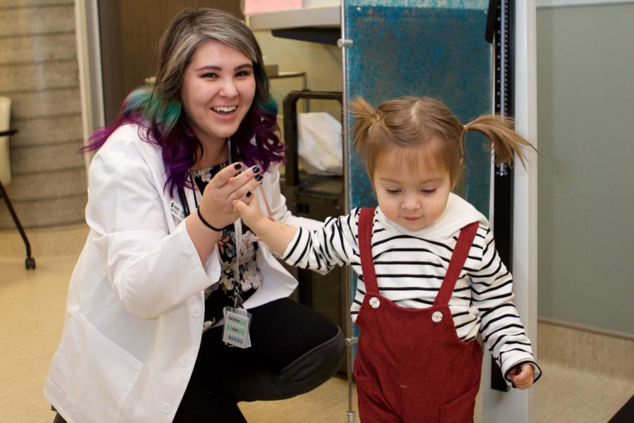 Physician holds the hand of a little girl in pigtails.